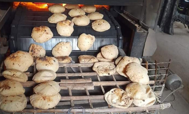 رغيف خبز بلدي طازج يخرج من سير الفرن الآلي داخل أحد المخابز